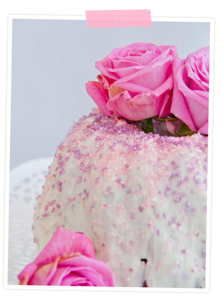 Prinzessinnen-Kuchen mit weißer Glasur und Glitzer. Dekoriert mit rosa Rosen